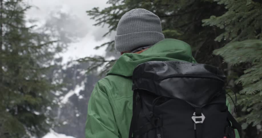 A man is hiking in a snow covered forest