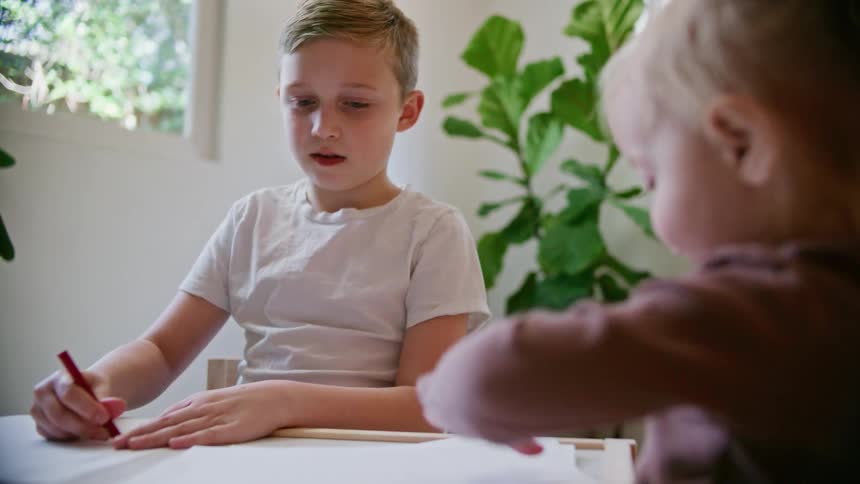 Two children coloring with crayons at a table