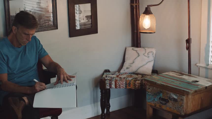 A man sitting in a room writing in a book