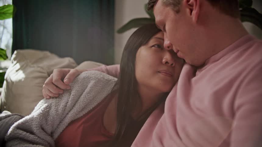 A man and woman hugging on a couch