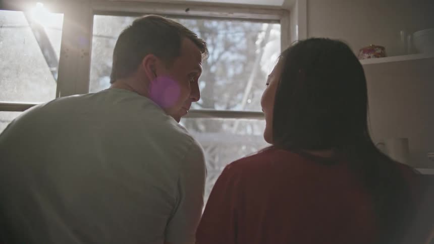 A man and woman sit inside at home and laugh and talk