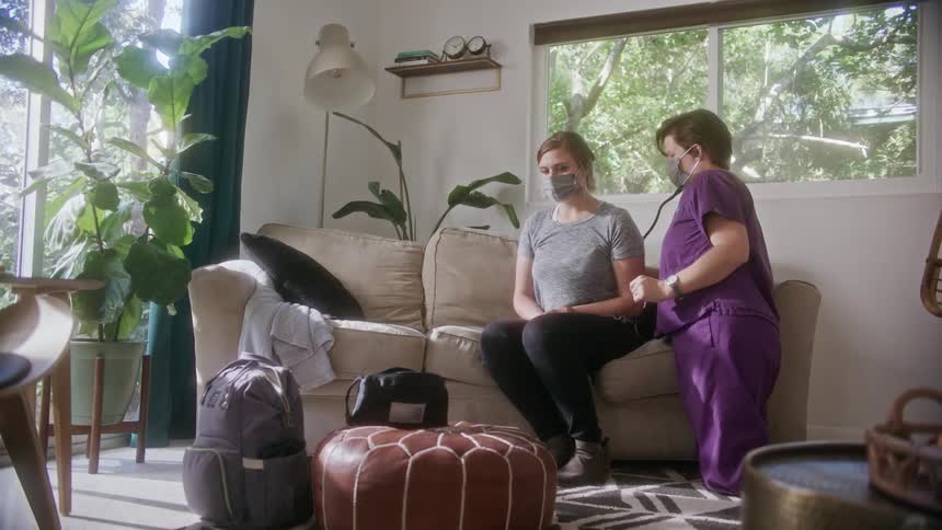 A doctor using a stethoscope on a patient on a couch
