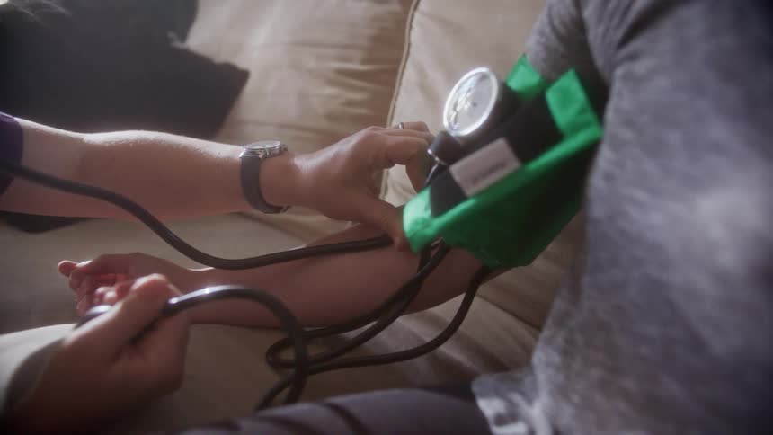 A person taking the blood pressure of a patient