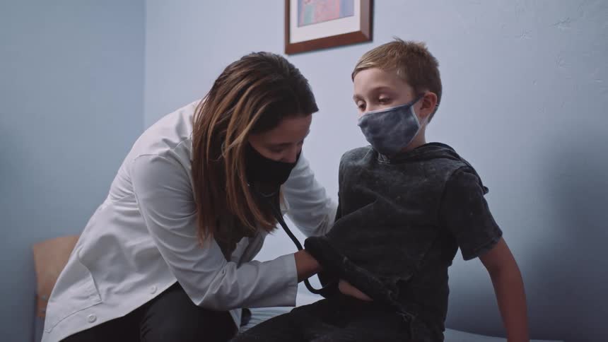 A doctor uses a stethoscope to check a young boys chest during a checkup
