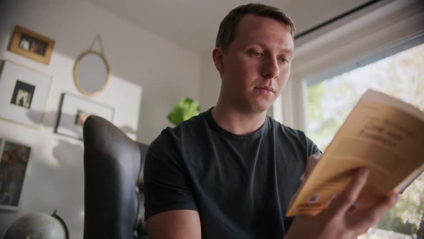 A man sitting in a chair reading a book