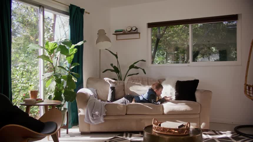 A kid sitting on a couch playing on a smartphone