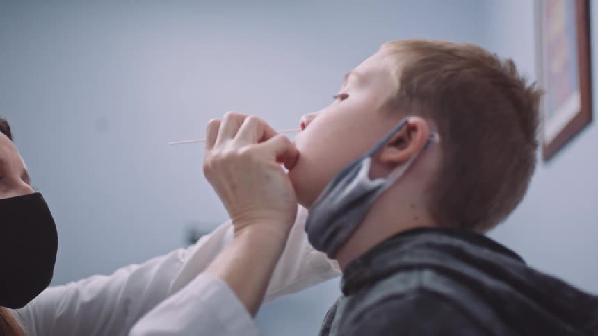 A female doctor uses a cotton swab to clean the nose of a boy in a doctors office