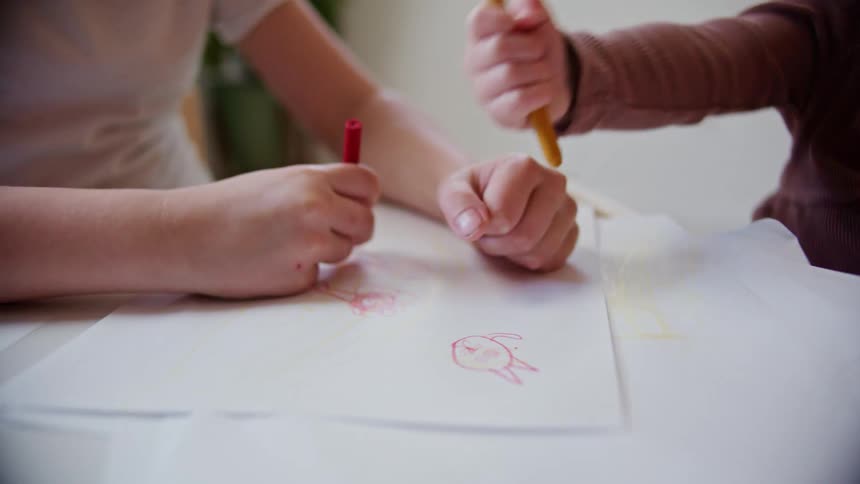 Two people drawing with crayons