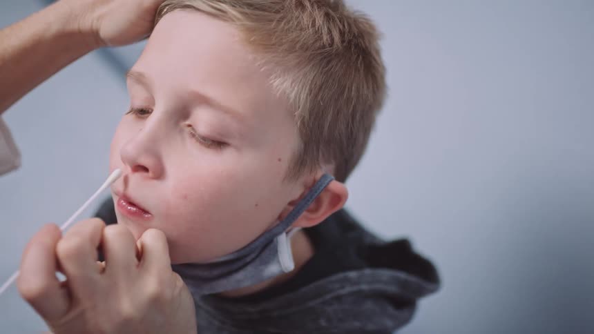 A person putting a cotton swab in a boys nose
