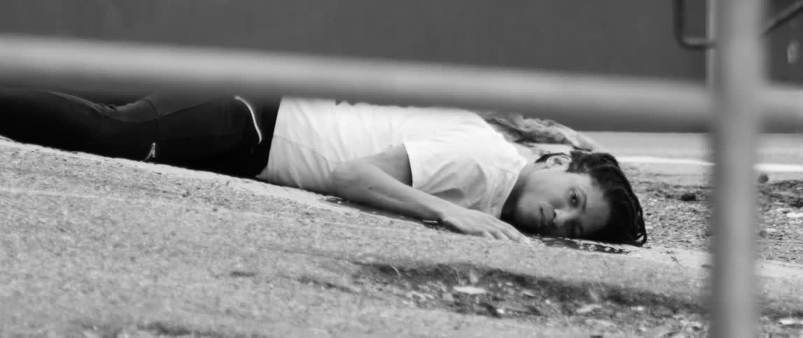 A woman lays on the ground and is not moving or blinking
