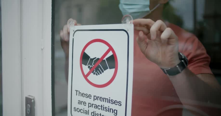 A man putting up a sign to encourage social distancing