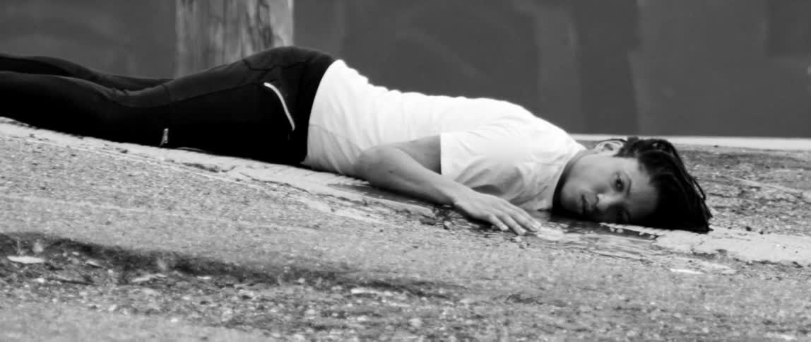 A man is lying face down on some rocks
