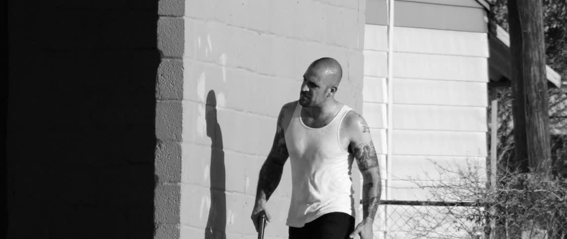 A man walking around a building with a gun in his hand