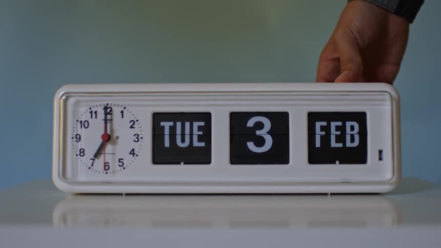 A persons hand is on an alarm clock