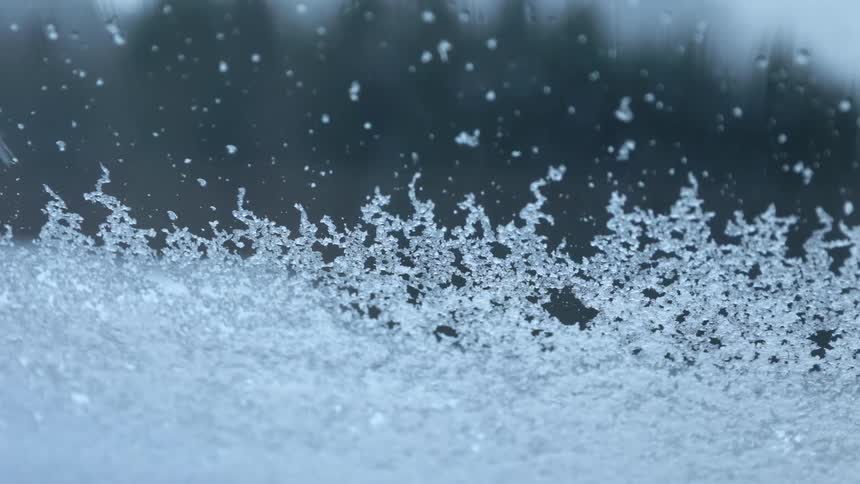 The snow is falling on the windshield
