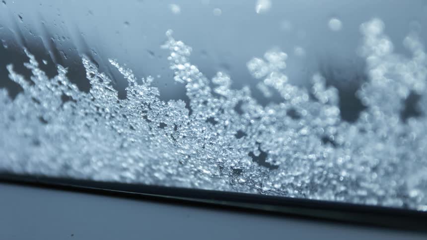 Ice building on a car window and rain running down it