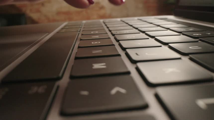 A woman is typing on a keyboard indoors