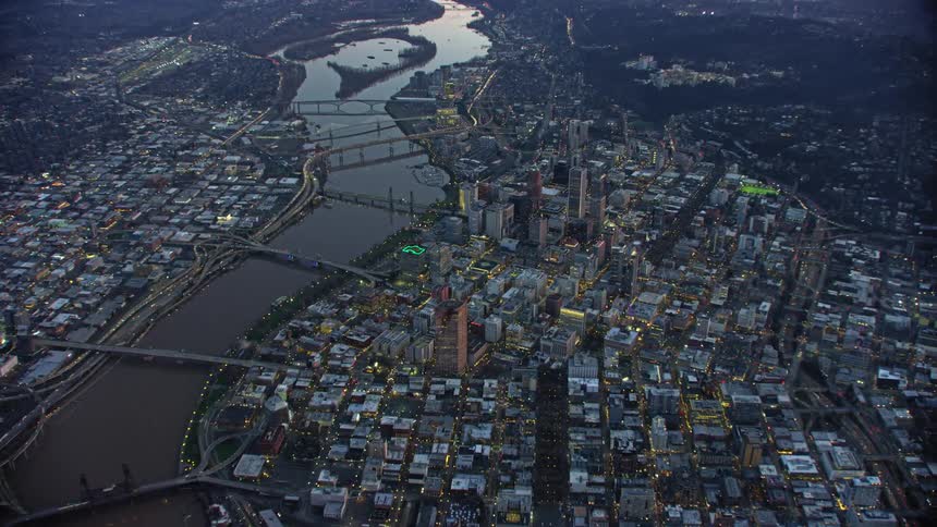 An aerial view of the Portland, Oregon city skyline with the Willamette River running through it reflecting beautiful sunset light