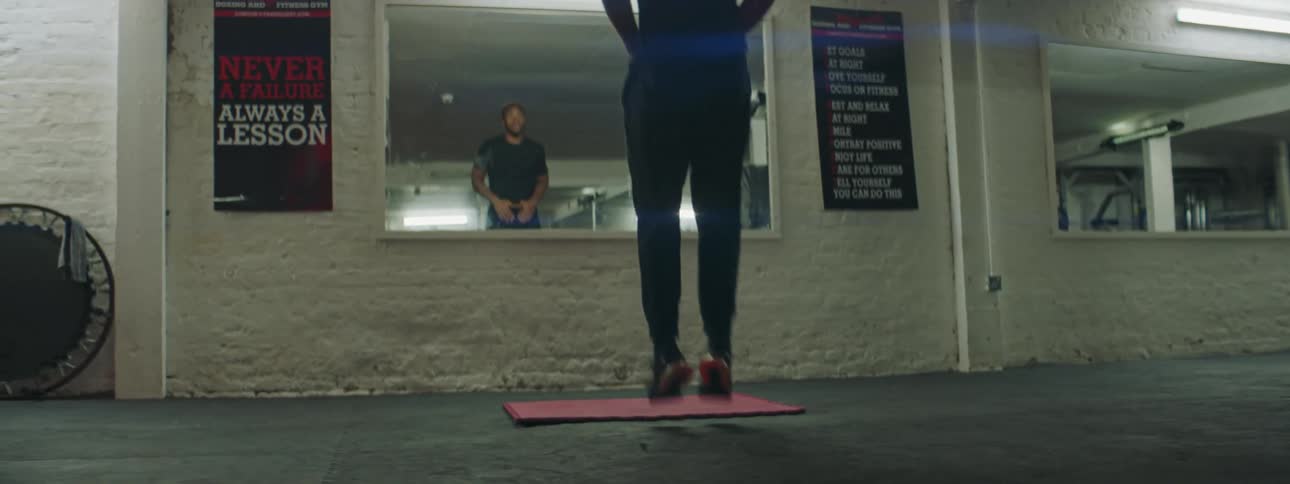 A man exercising indoors jumps up and down