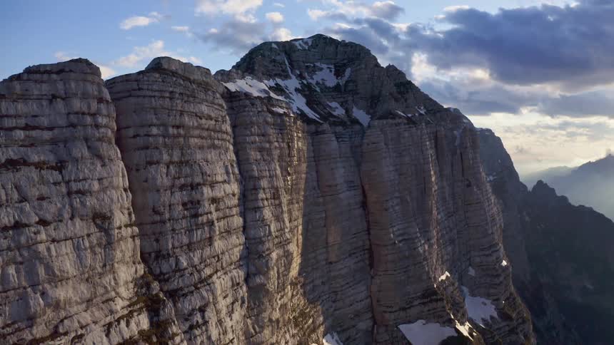 Aerial view of the snow covered steep cliffs on a mountain range at morning