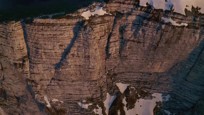Aerial view of the snow covered steep cliffs of a mountainside at morning