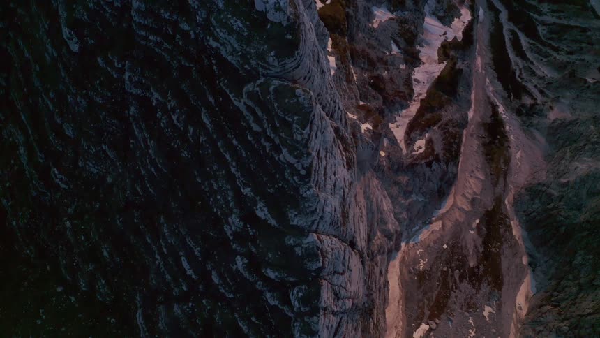 Aerial view of the snow covered steep cliffs on a mountain range at morning