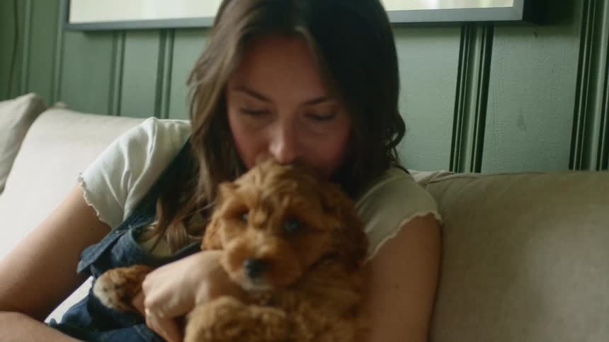 A woman kisses her dog on the couch