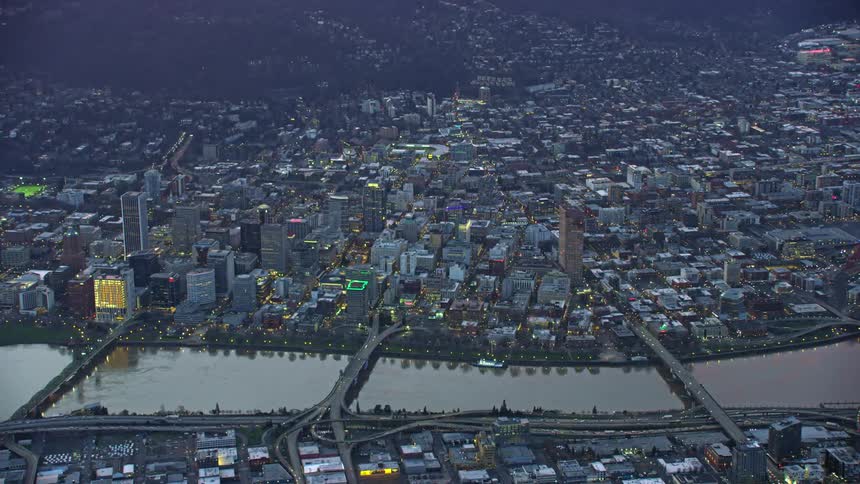 Portland, Oregon. An aerial view of the Willamette River flowing through a large city with skyscrapers in this high altitude aerial after sunset