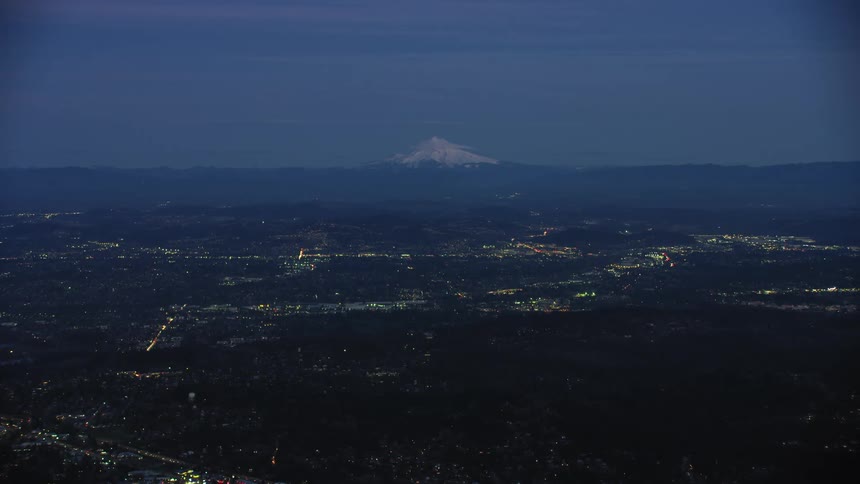 Blue Hour aerial view of the Portland, Oregon suburbs near the tall snow covered mountain peak of Mount Hood