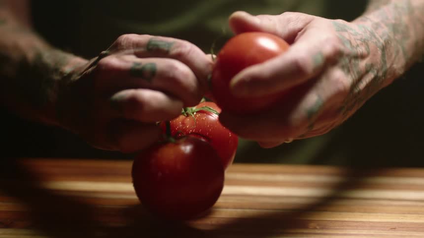 A person grabbing a tomato off a vine