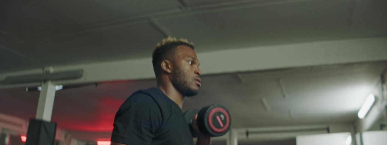 A man is lifting two barbells in the gym