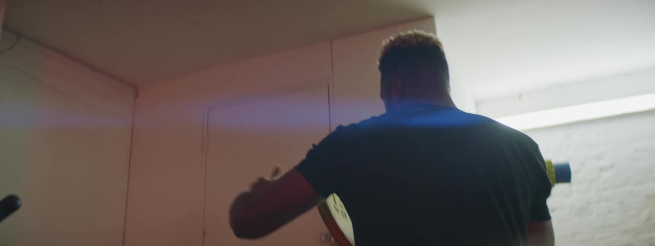 A man in a gym putting a weight on a bar then exercising