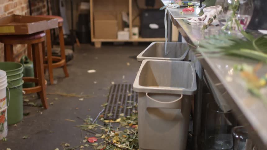 Stems, leaves and plant scraps litter the floor of a flower shop work area