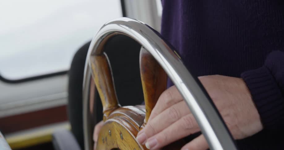A person steering a wheel on a boat