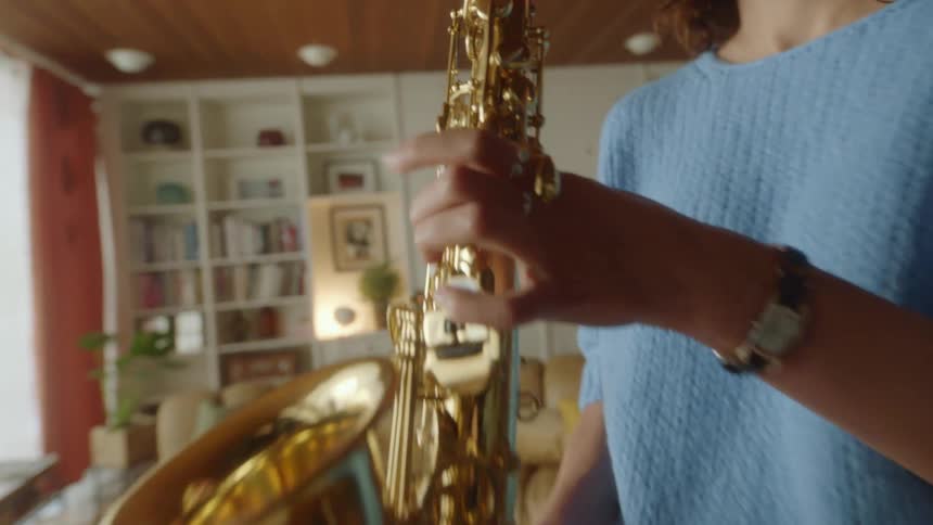 A woman playing a saxophone in a living room