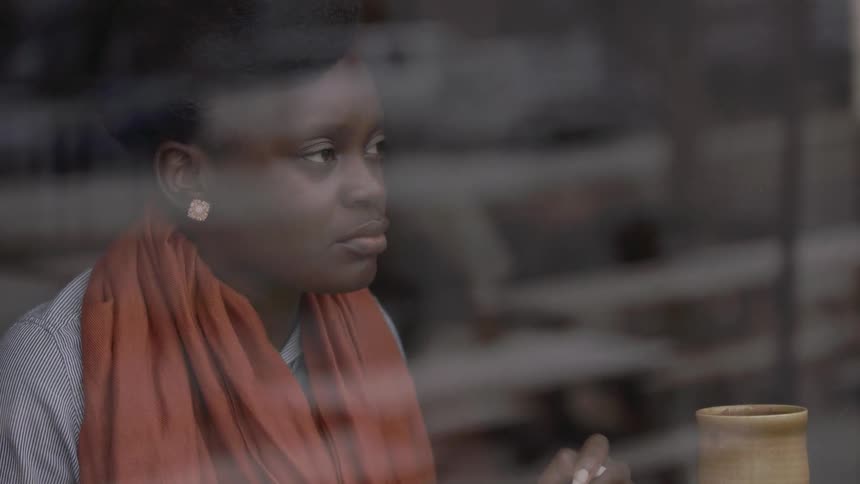A woman in an orange scarf looks out of a window