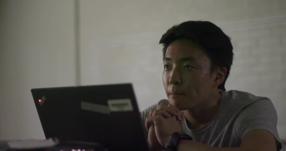 A young man sits and listens attentively while his laptop computer is open in front of him