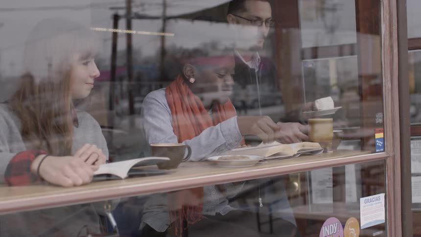 Women sitting at a coffee shop counter while reading