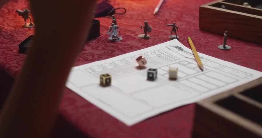 A teenager rolls dice while playing a tabletop game