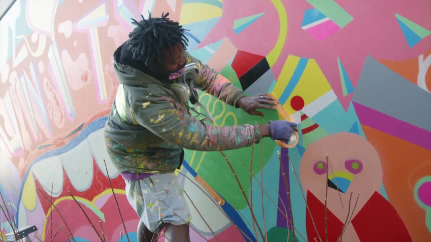 A painter putting tape on a wall at a mural