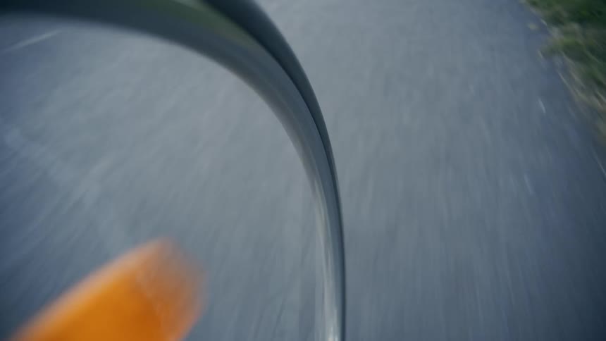 A bicycle riding down a path next to grass POV