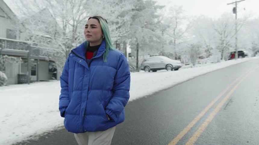 A woman is walking outdoors in winter through a neighborhood