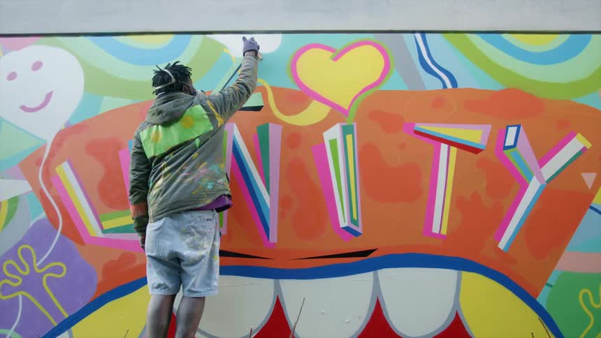 A man spray painting on a mural
