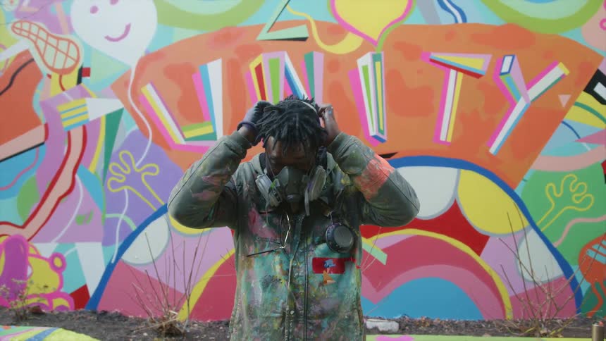 A man is standing by a painted wall outdoors