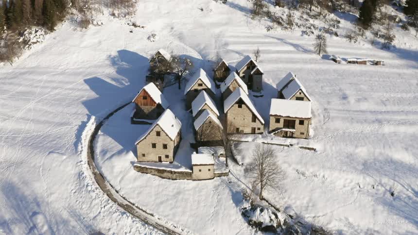 A village with houses covered in snow surrounded by trees
