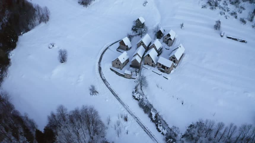 A few buildings surrounded by a snow covered field