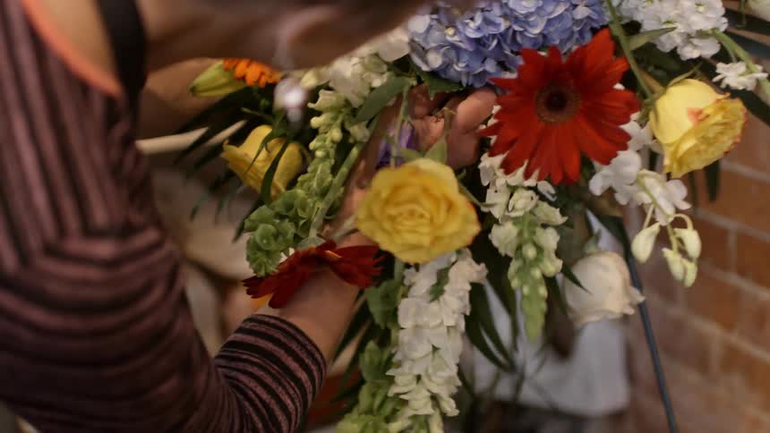 Florist inserting a yellow rose into an arrangement