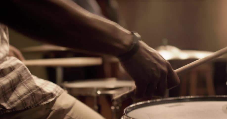 A man playing a cello as another man plays the drums