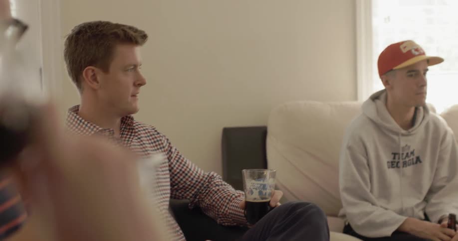 A man takes a drink as others talk