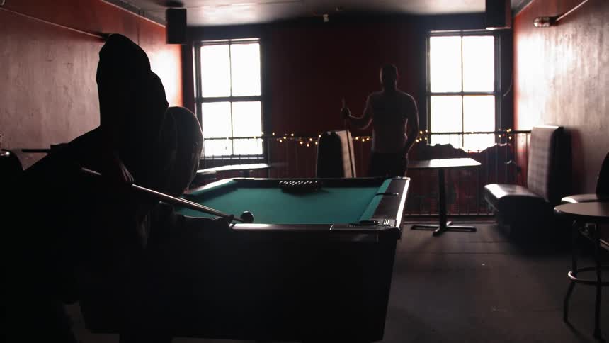 Two men play billiards in a bar